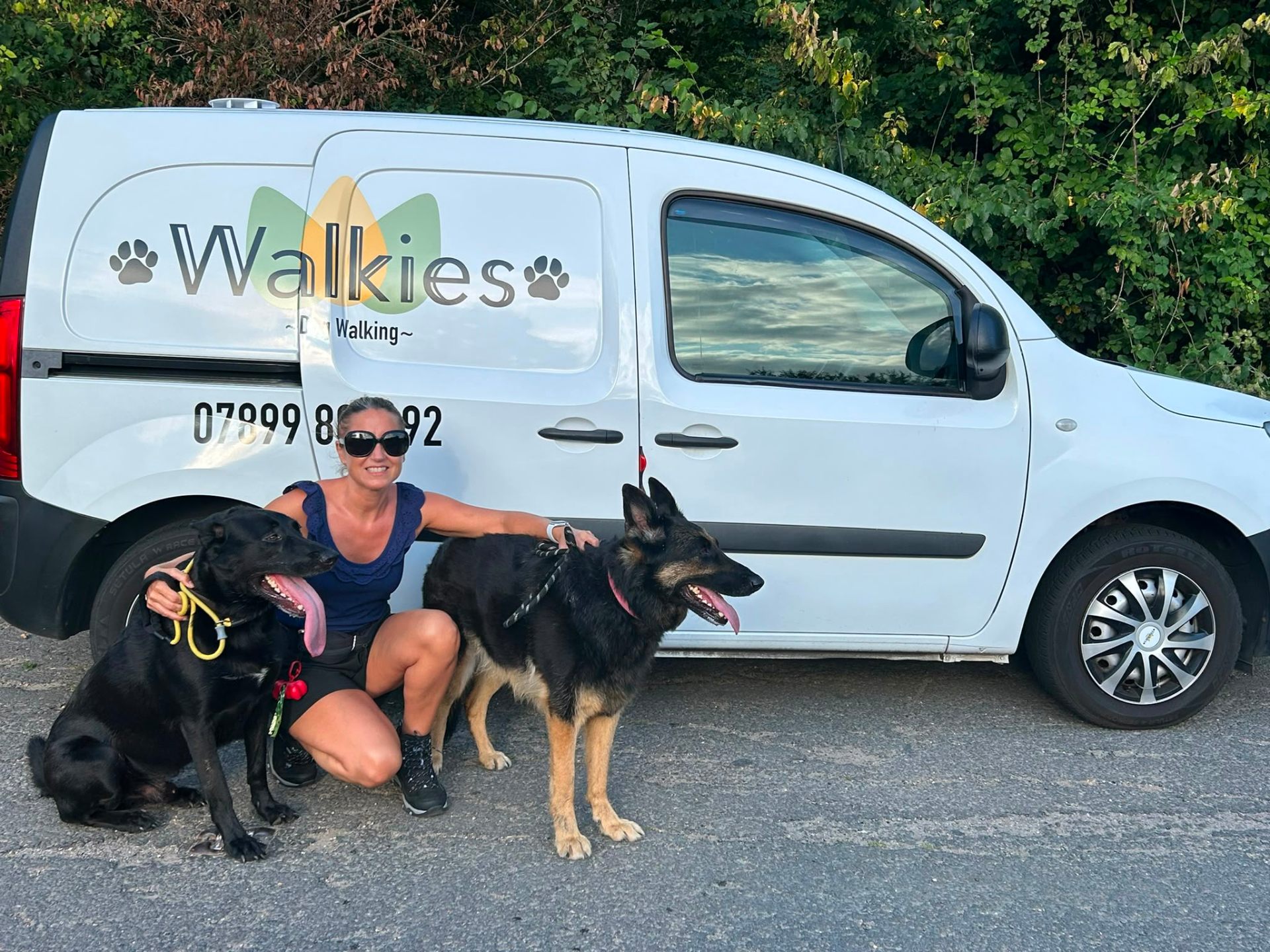 Lisa with two happy dogs in front of the Walkies van